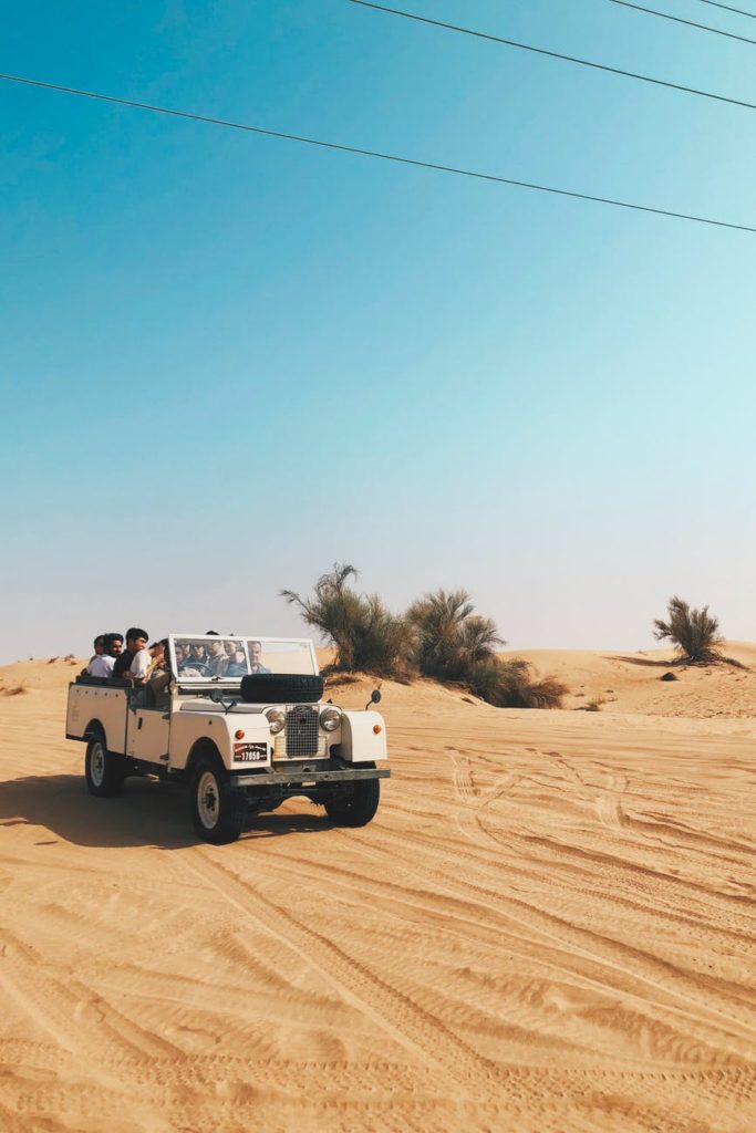 people riding vehicle on desert